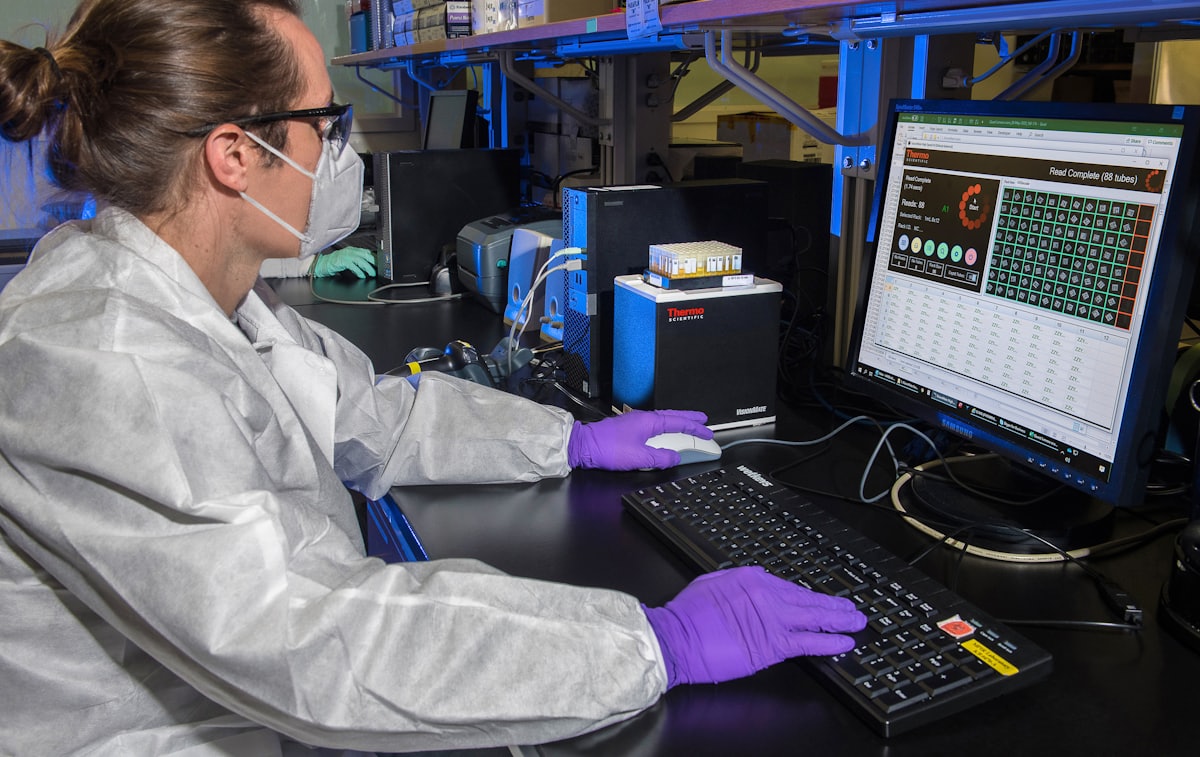 Engineer in a white coat at a quality-control workstation in a production environment